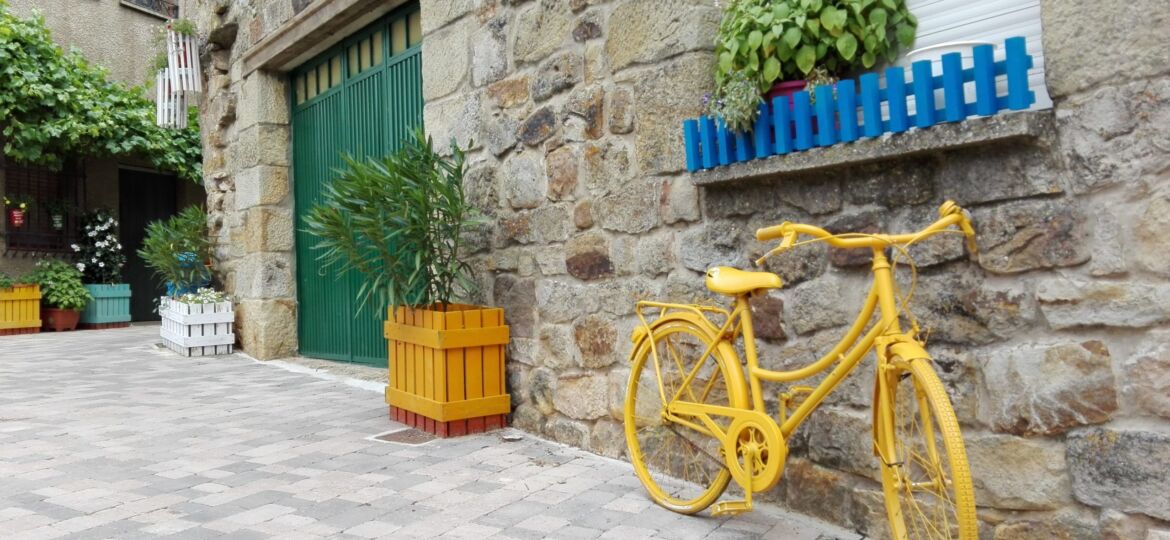 Rincón de una calle donde hay una bicicleta amarilla y varios maceteros